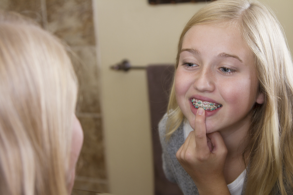 Teen girl looking in the mirror, examining her braces